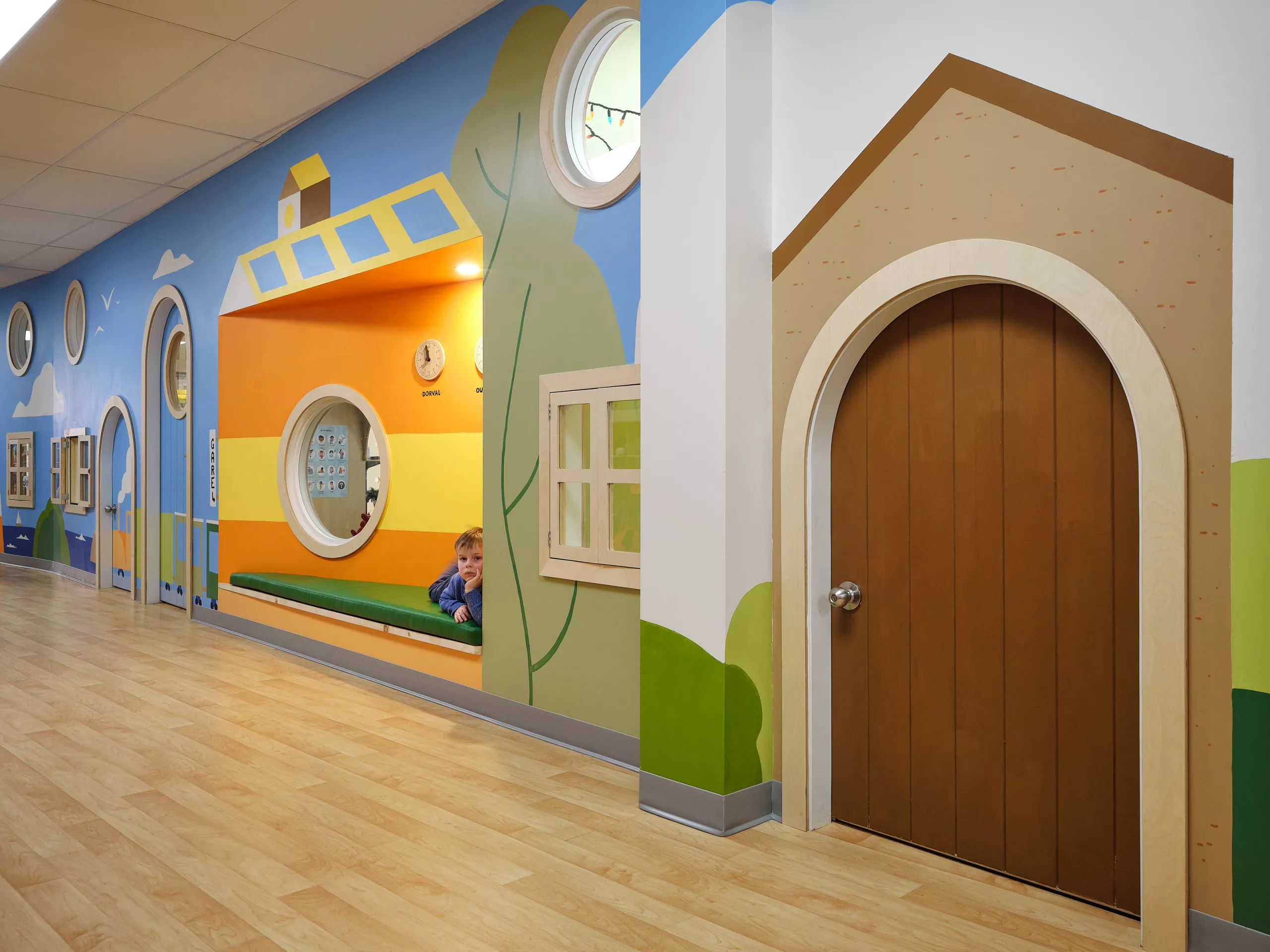 Vue rapprochée du corridor au sous-sol du Collège Sainte-Anne Buissonnière. On y voit les portes de classes arrondies et la murale peinte à la main par Lucas Saenger.