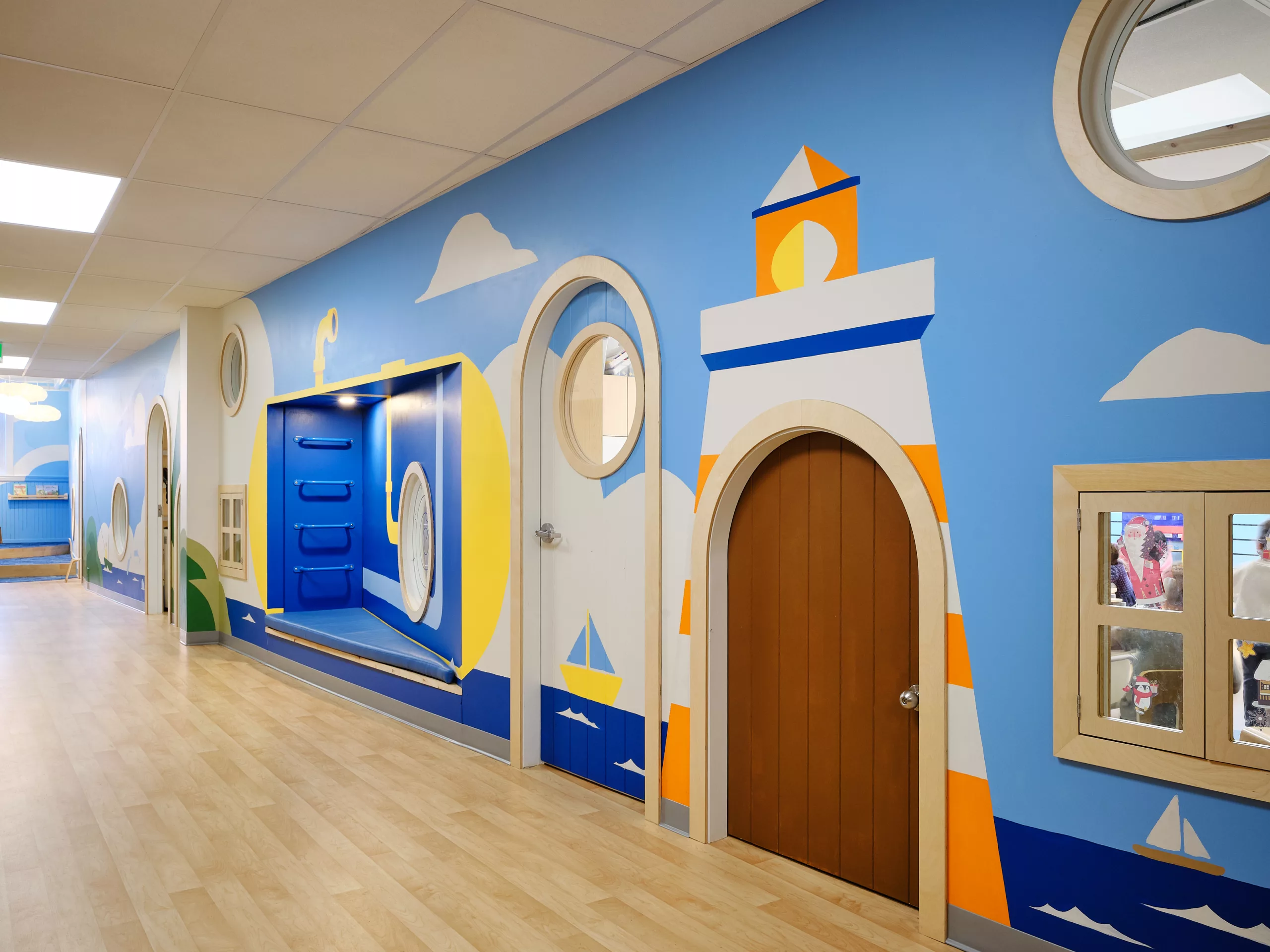 Vue rapprochée du corridor au sous-sol du Collège Sainte-Anne Buissonnière. On y voit les portes de classes arrondies et la murale peinte à la main par Lucas Saenger.