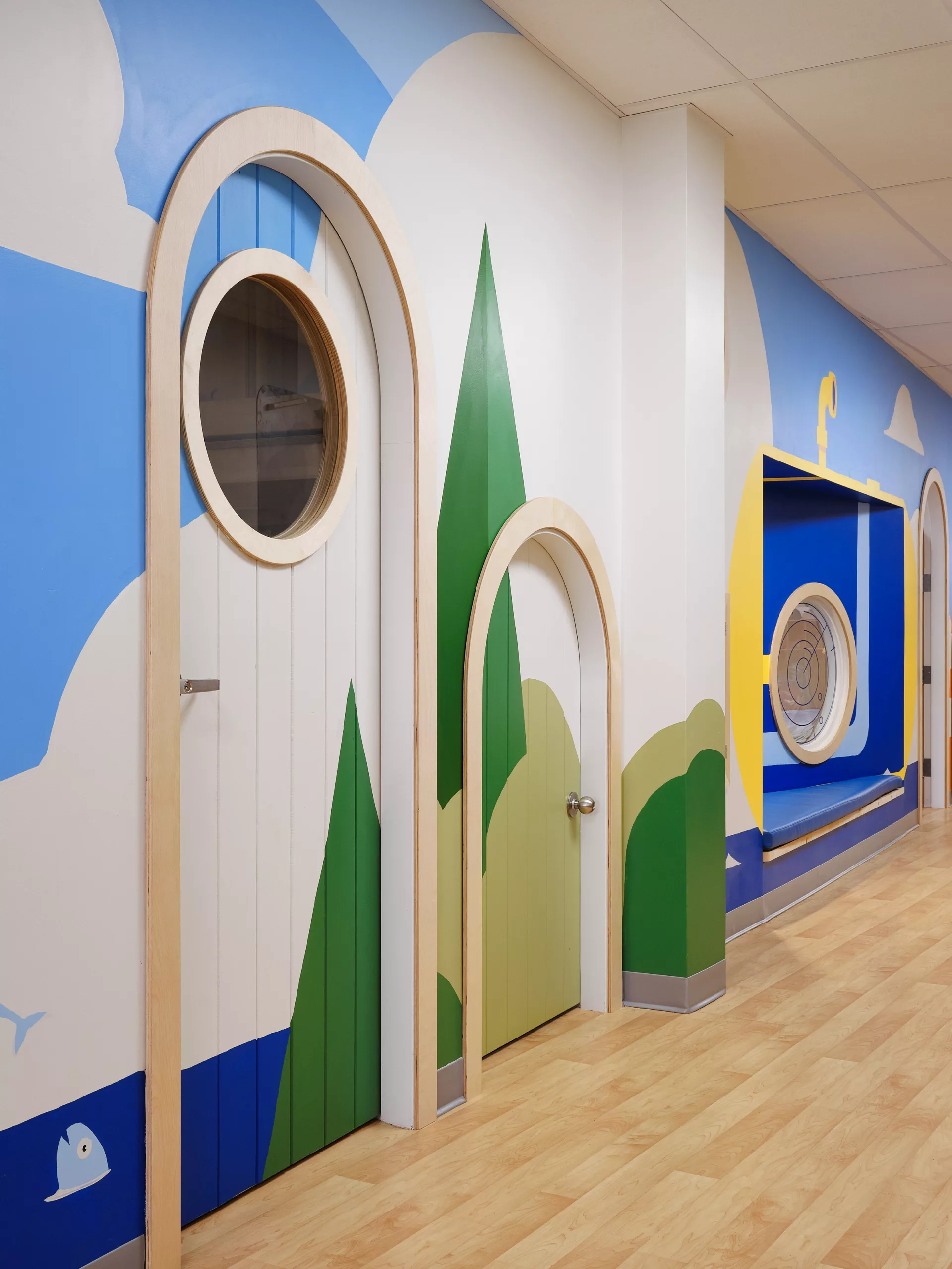 Vue rapprochée du corridor au sous-sol du Collège Sainte-Anne Buissonnière. On y voit les portes de classes arrondies et la murale peinte à la main par Lucas Saenger.
