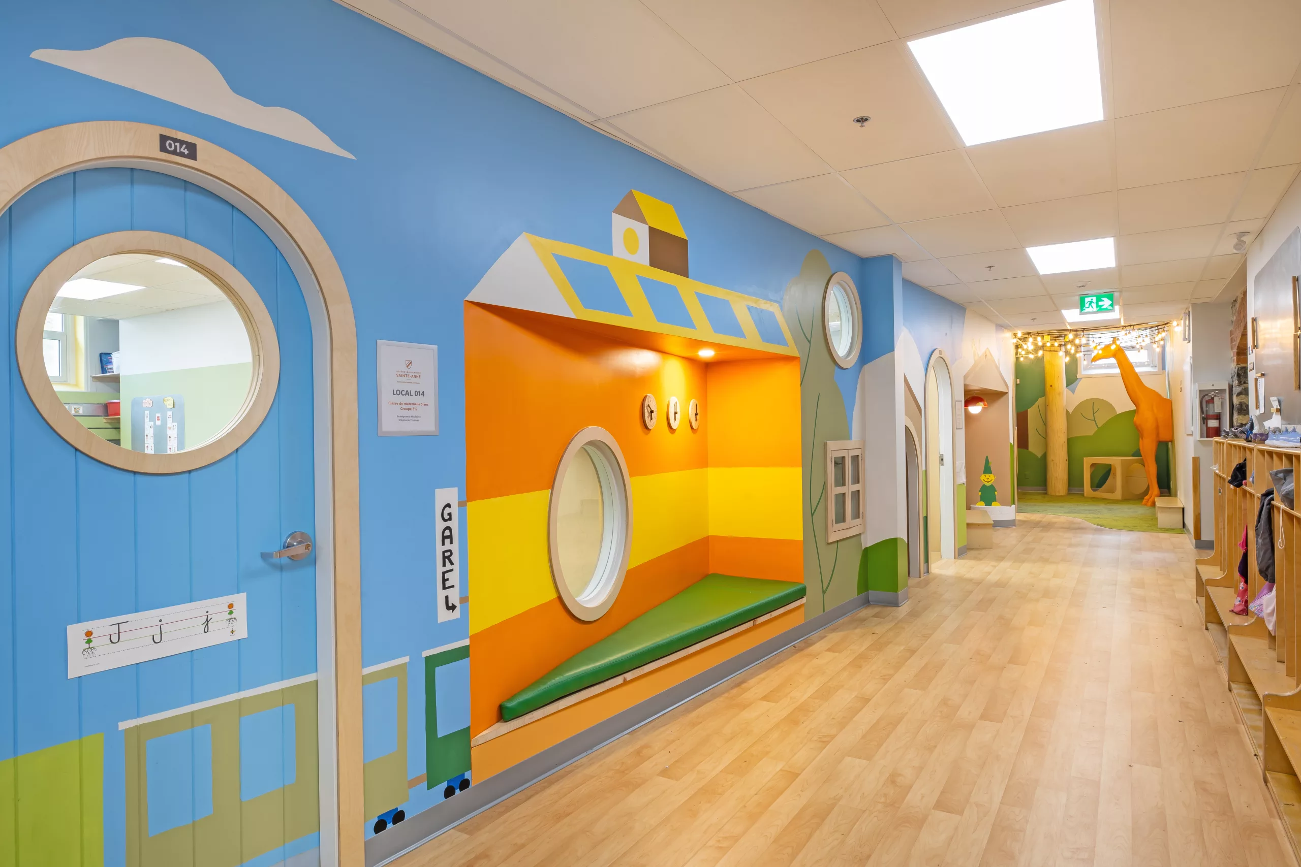 Vue rapprochée du corridor au sous-sol du Collège Sainte-Anne Buissonnière. On y voit les portes de classes arrondies et la murale peinte à la main par Lucas Saenger.