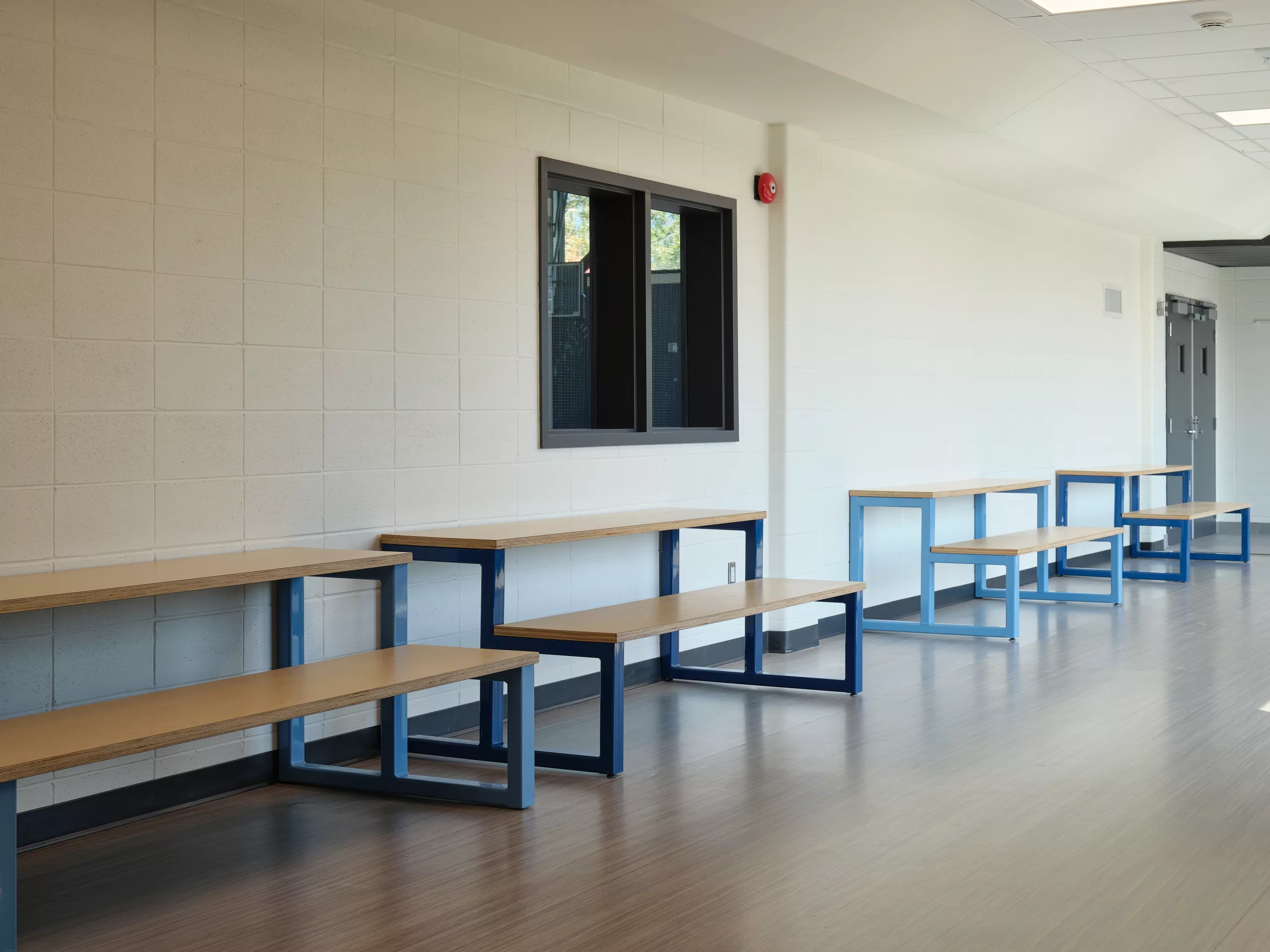 Une vue d'un couloir montrant quater bancs-comptoirs Bantam d'acier et de bois, de la collection de mobilier conçu et fabriqué par Taktik Design. 