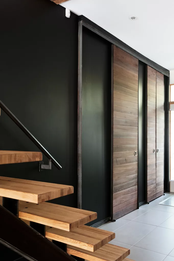 Mur avec portes de lattes de bois foncées devant l'escalier.
