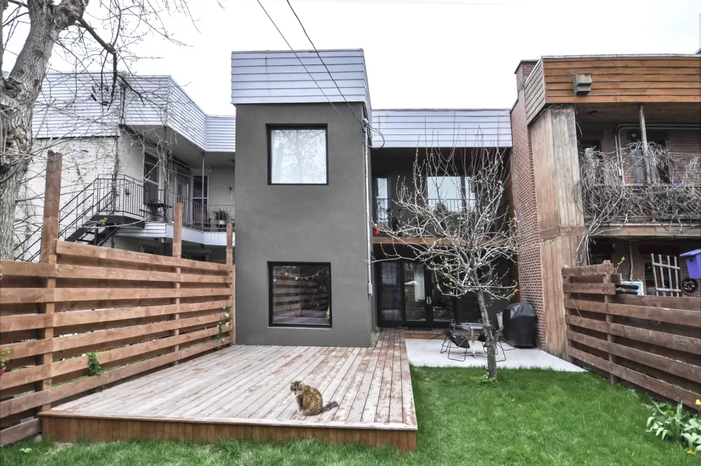 La cour du duplex Saint-Vallier démontre les grandes fenêtres de l'arrière du bâtiment, ainsi qu'un chat assis au bout de la terrasse.