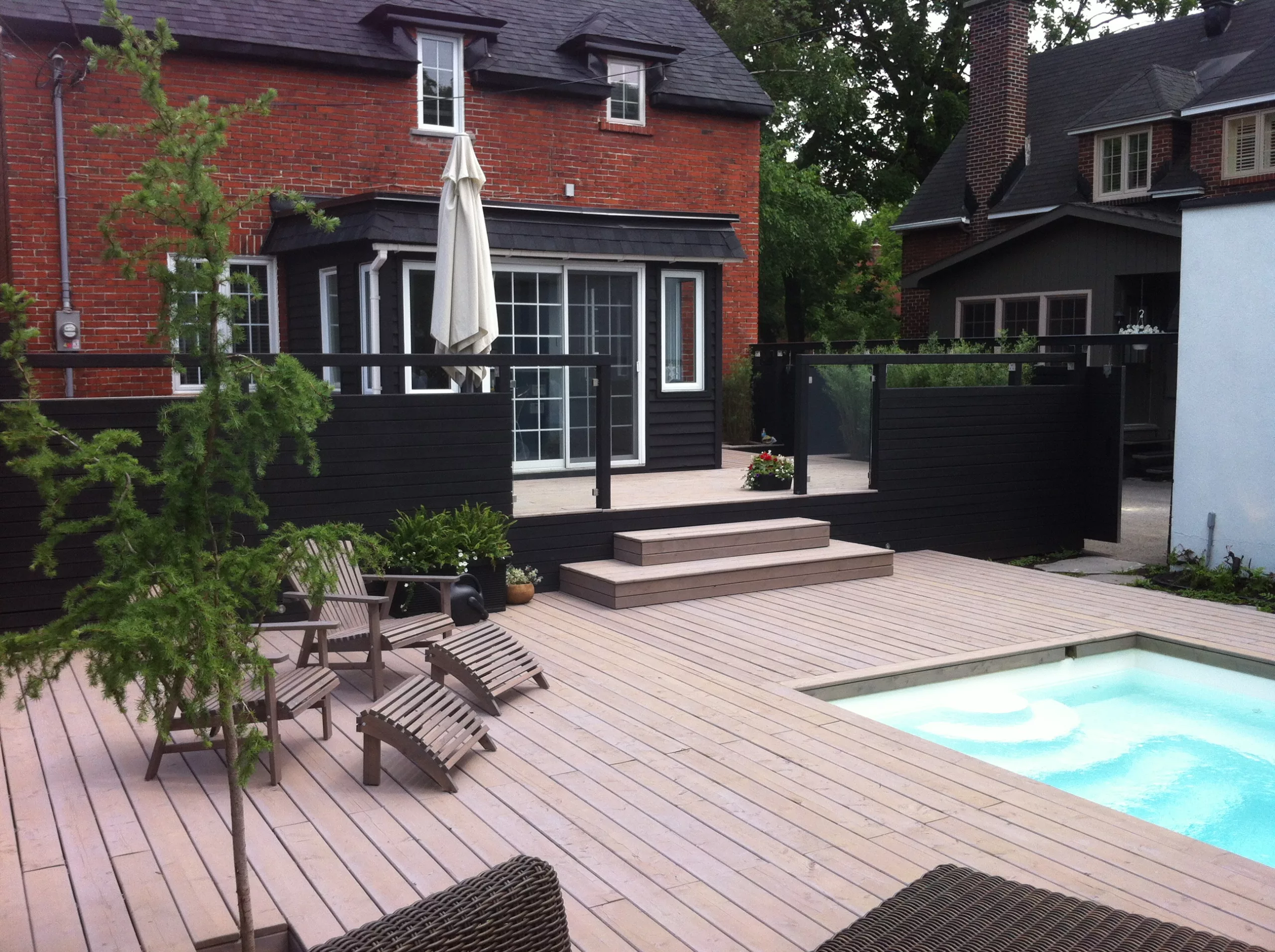 Vue de la terrasse de Johanne vers la maison, ou l'on aperçoit un arbre et la piscine.