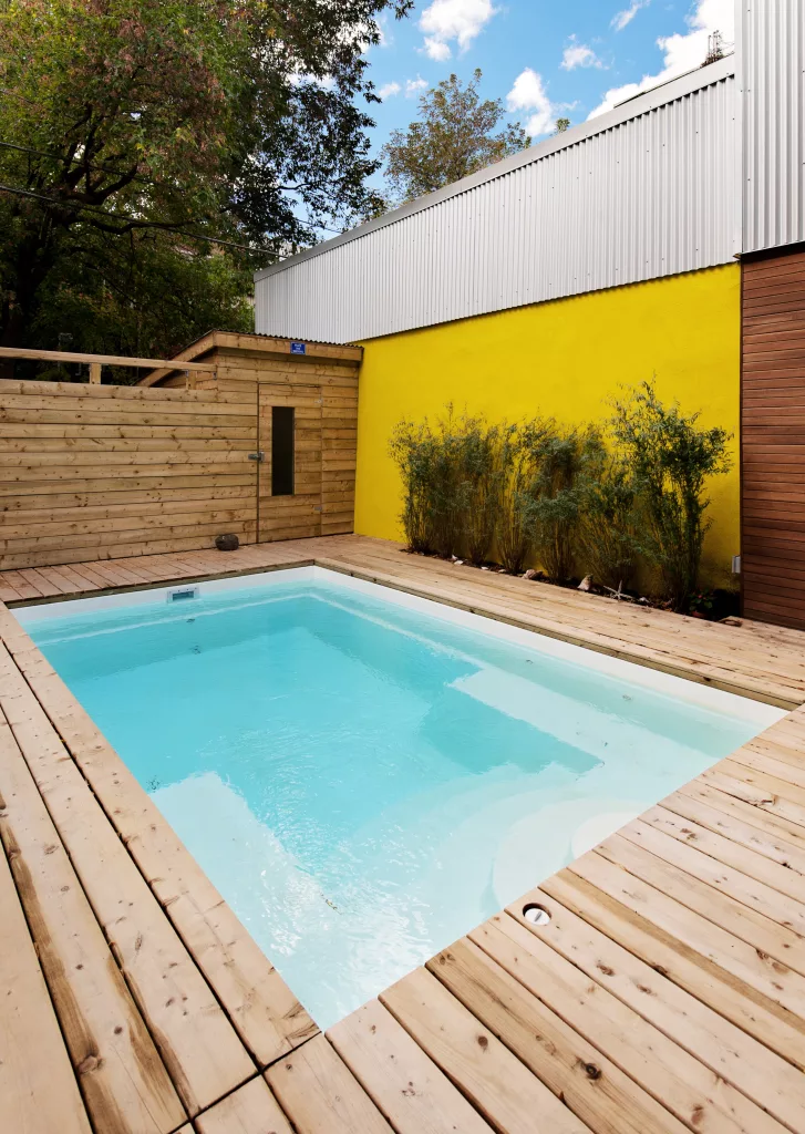 La piscine creusée est encastrée dans le patio de bois derrière le triplex.