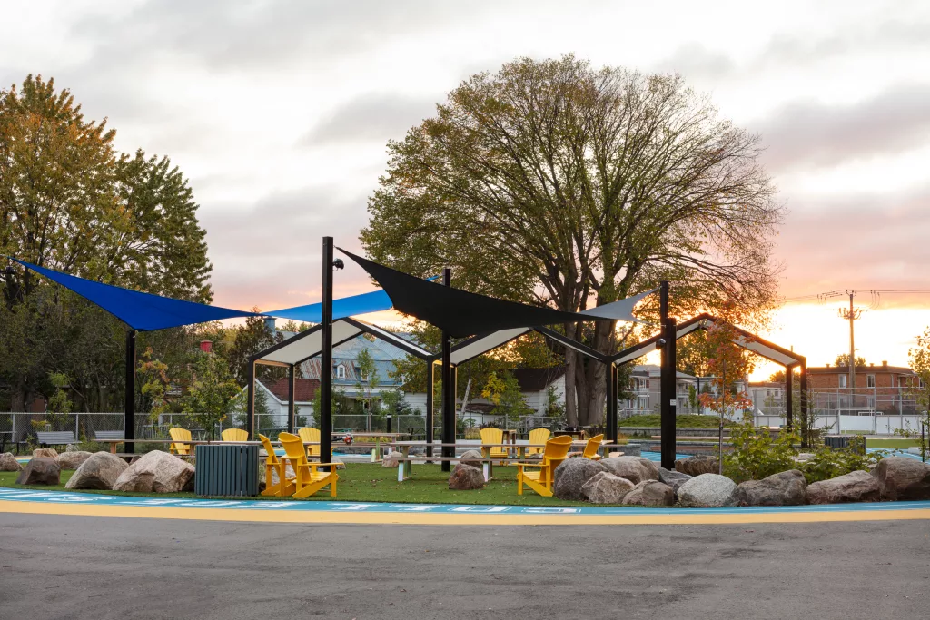 Une section de l'intérieur de la piste de course à pied comprend des chaises Adirondack jaunes, des pierres disposées sur du gazon synthétique et des tables de picnic.