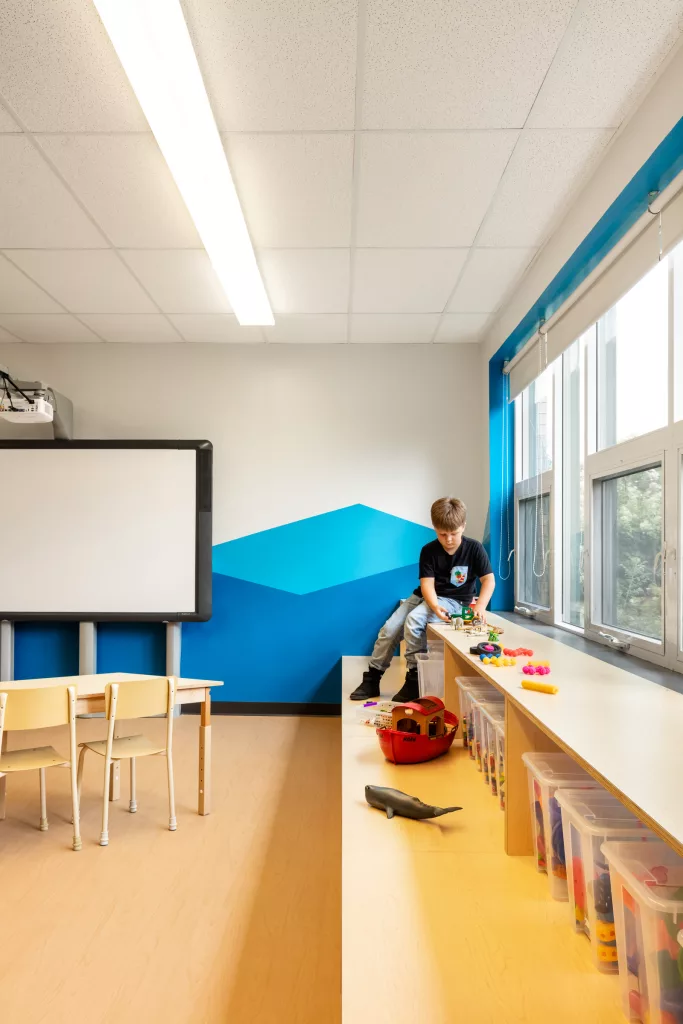 Une petite estrade comprenant du rangement fait partie du mobilier hors de l'ordinaire pour une salle de classe.