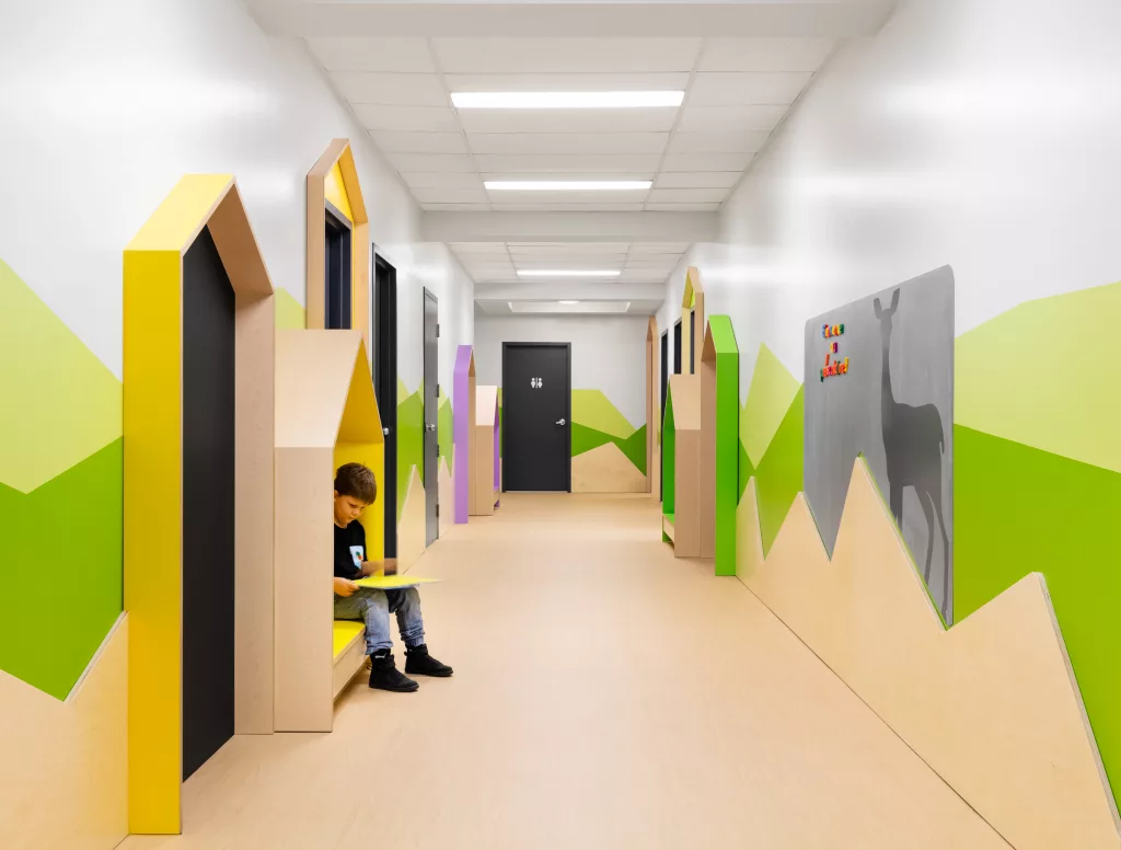 Le corridor qui sépare les lasses comprend des banquettes en forme de maisonettes, des couleurs vives et des tableaux.