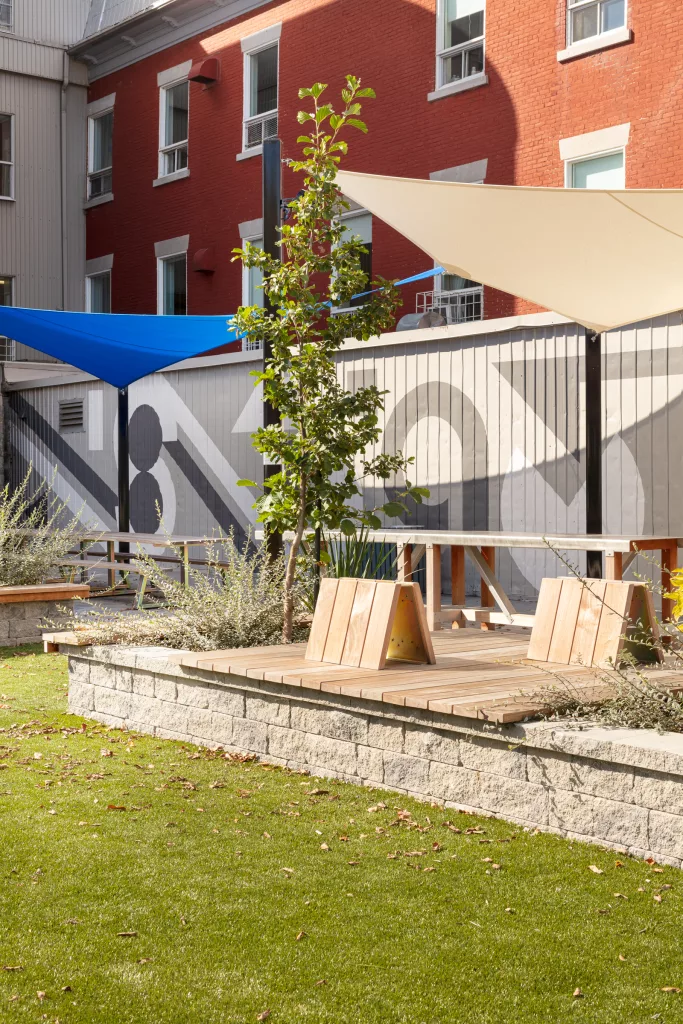 Des banquettes de bois on été ajoutées à des murets de pierre pour ajouters des espaces ou les jeunes peuvent s'assoir dans la cour du Collège Saint-Paul.
