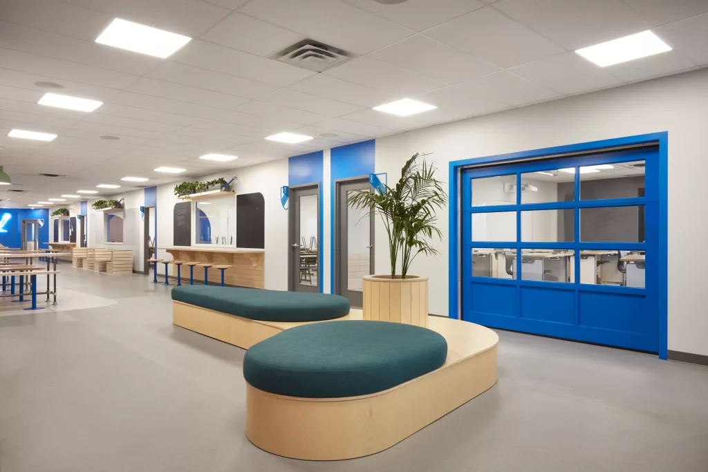 Une vue opposée du banc aux formes arrondis devant une classe ayant une porte de garage vitrée de couleur bleue.