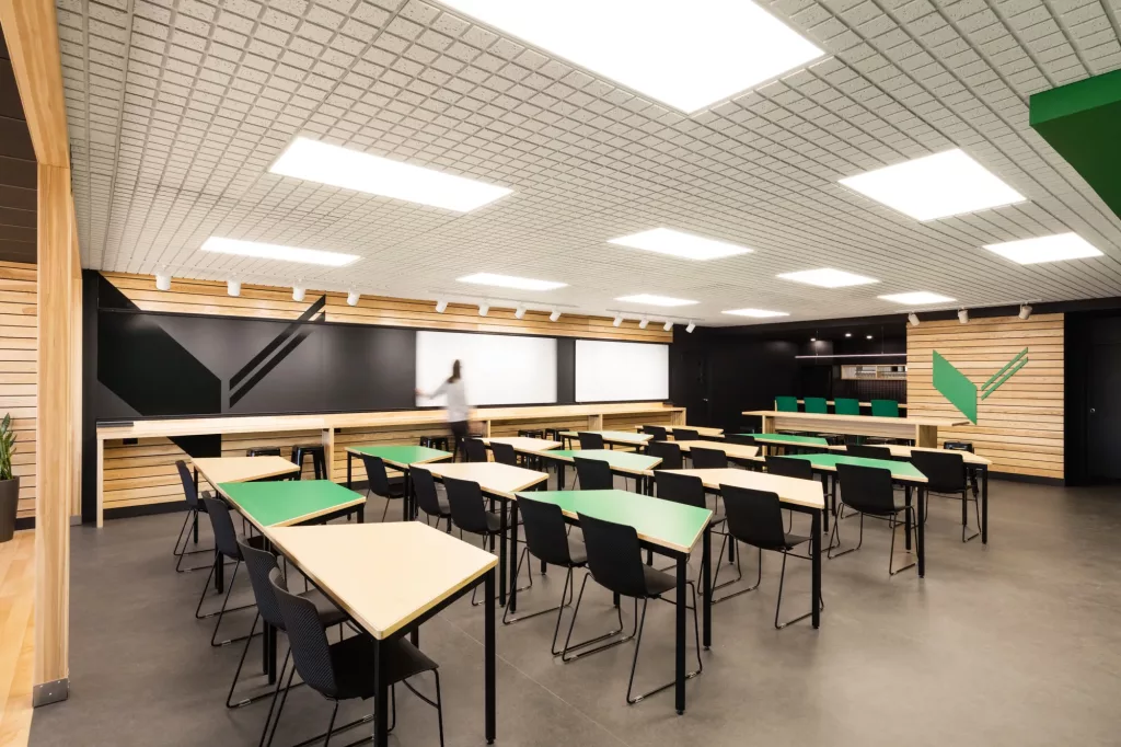 Une personne déplace un tableau blanc sur le mur du fond de salle multifonctionnelle Le Belvédère de l'Externat Sacré-Coeur.
