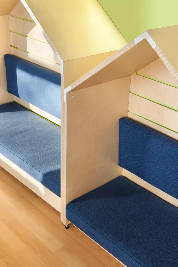 Vue rapprochée des banquettes de la bibliothèque. La lumière naturelle rentre par les fenêtres et habille les meubles.