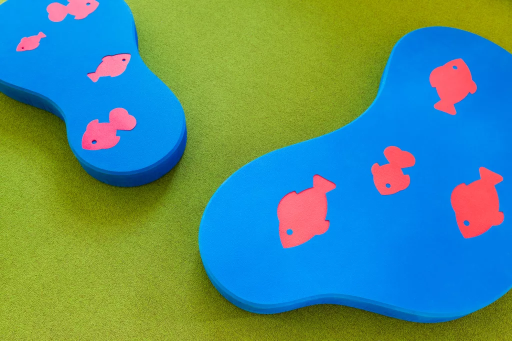 Gros plan sur un détail graphique dans l'aménagement de la bibliothèque. Taktik Design a créé des formes en mousse découpée qui s'imbriquent. Elles représentes des lacs et des poissons.