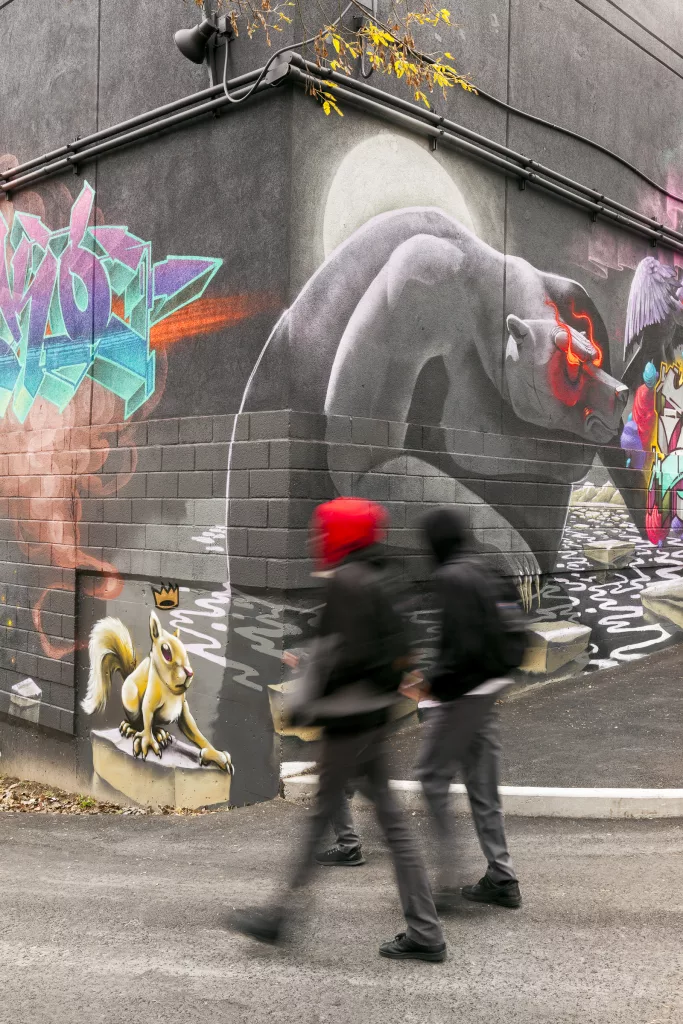 DEux élèves marchent devant un mur de graffiti de la cour extérieure du Collège Ville-Marie.