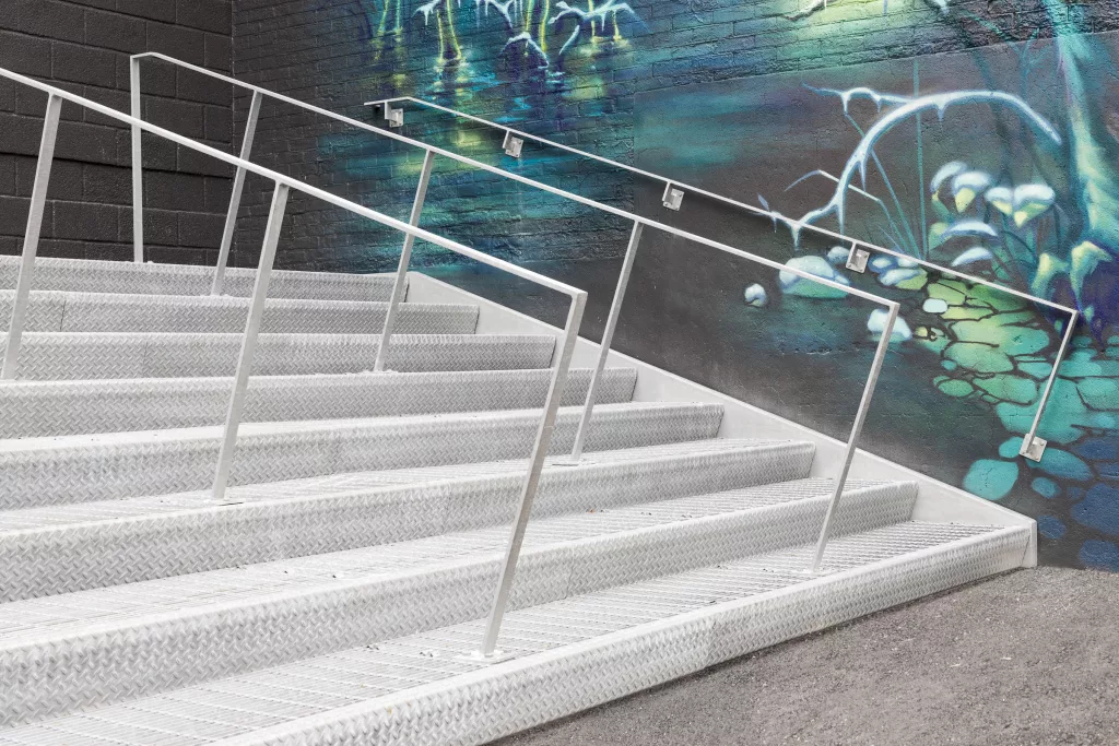 Un immense escalier d'acier galvanisé devant un mur de graffiti à l'entrée des élèves de la cour arrière du Collège Ville-Marie.