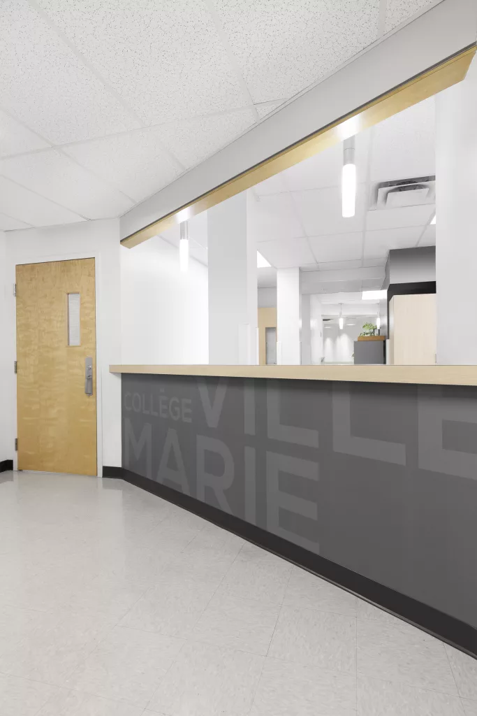 Le comptoir d'administration est tapissé du nom du collèe en gris ton sur ton.
