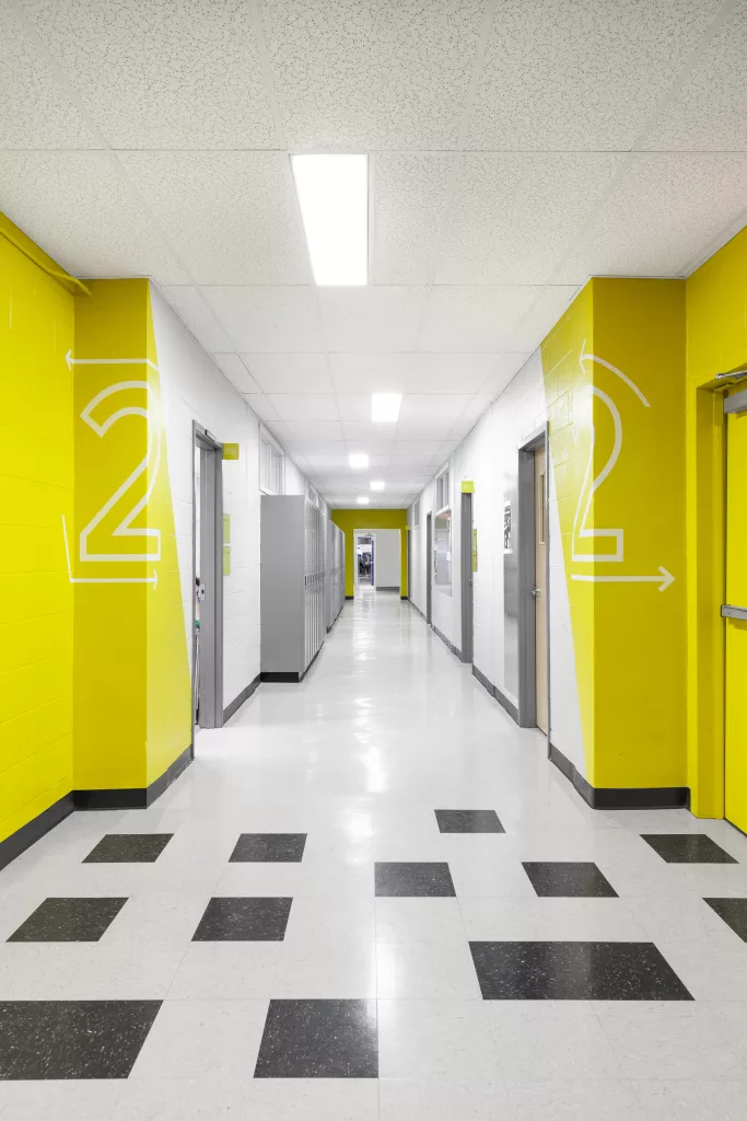 Un corridor du collège Ville-Marie ou la couleur jaune accentue les coins, et des plaquettes d'acier de la même couleur identifient chaque local.