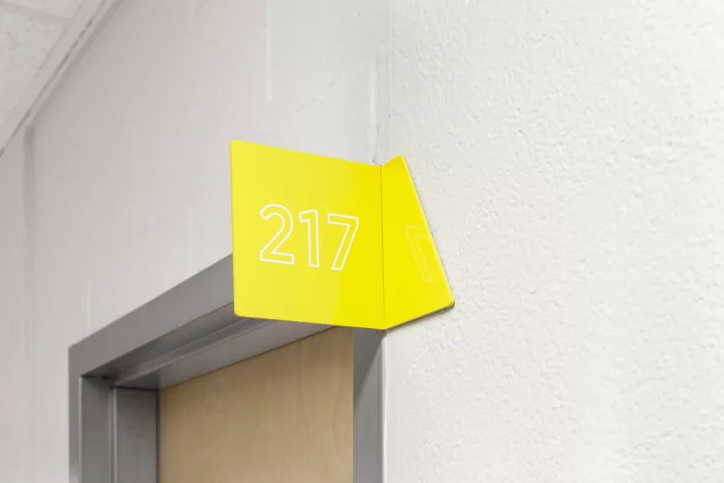 Une  braquette d'acier de couleur jaune ou est inscrit le numéro d'un local.
