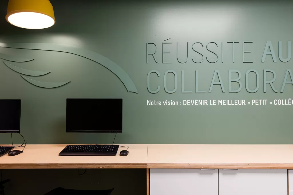 Des postes de travail dans la section opposée à la cuisine comprend le logo du collège et un mantra des enseignants appliqué au mur ver en ton-sur-ton.