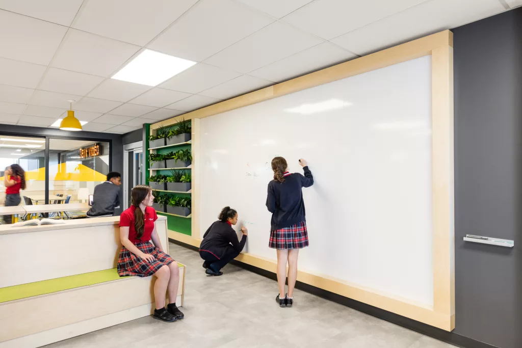 Un imense tableau blanc près du mur de biophilie de la bibliothèque du Collège d'Anjou.
