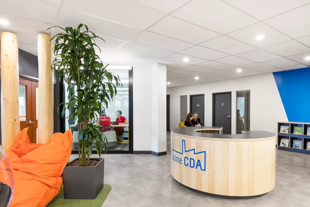 Un grand bureau de réception en bois se trouve à l'entrée de la nouvelle bibliothèque du Collège d'Anjou.