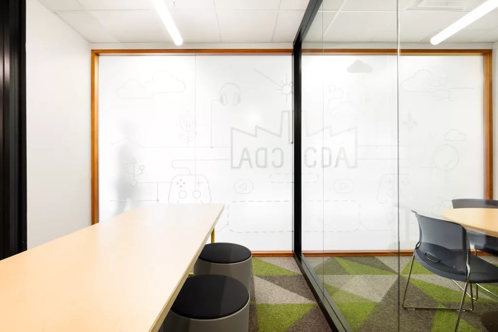 Un mur vitré laissant entrer la luminosité d'une salle de travail fermée.