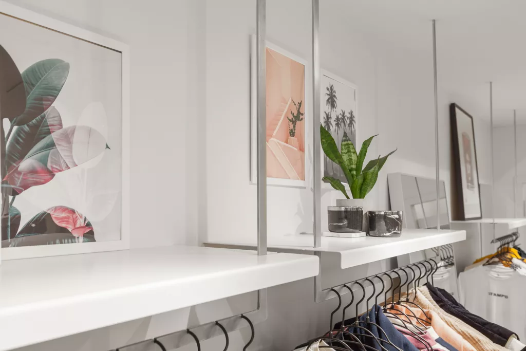 Des images de plantes triopicales décorent des tablettes au-dessus d'un présentoir de vêtements  de la boutique Status.