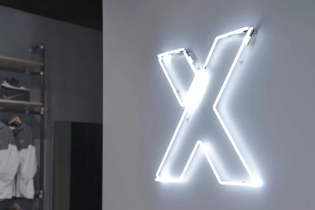 Le mur du fond de la boutique comprend le logo en néon blanc sur fond blanc.