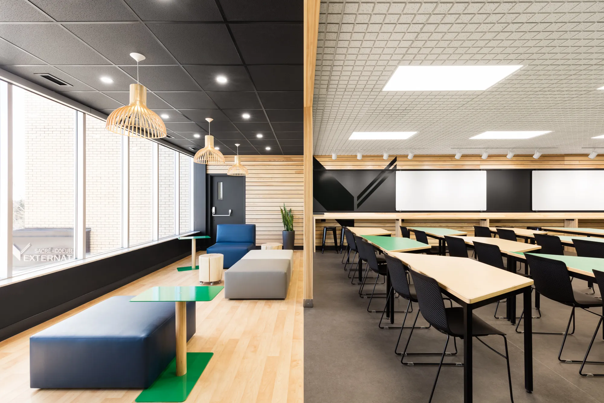 Le design de la salle multifonctionnelle Le Belvédère de l'externat Sacré-Coeur comprend un espace salon près du mur fenestré et des bureaux modulables dans la section de travail.