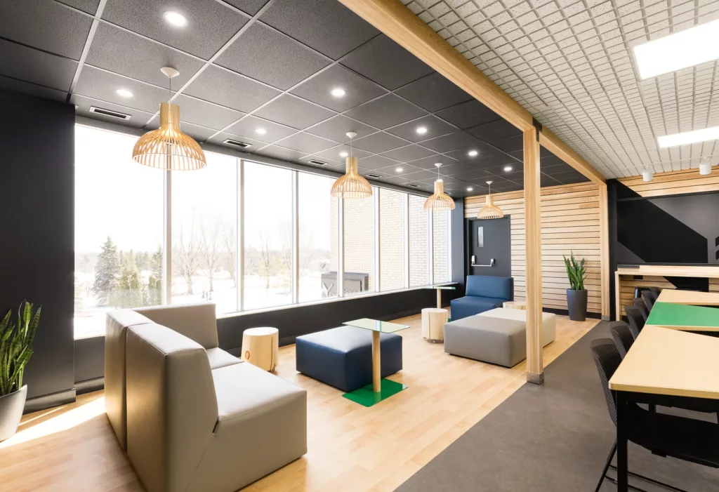 salle multifonctionnelle Le L'espace salon du Belvédère de l'Externat Sacré-Coeur comprend des lampes suspendues aux formes de bois d'une silouette de style industrielle.