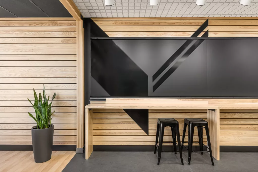 Le mur principal de la salle multifonctionnelle Le Belvédère de l'Externat Sacré-Coeur comprend des tableaux blancs mobiles et des comptoirs de bois clair.