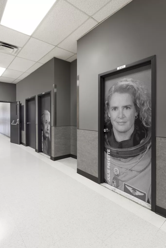Un corridor où des photos de personnes inspirantes tapissent les portes.