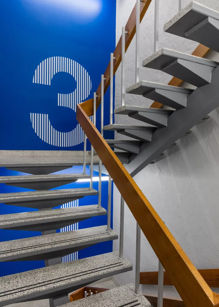 La main courante de l'escalier en bois s'agence agéablement avec le bleu d'un mur de l'escalier.