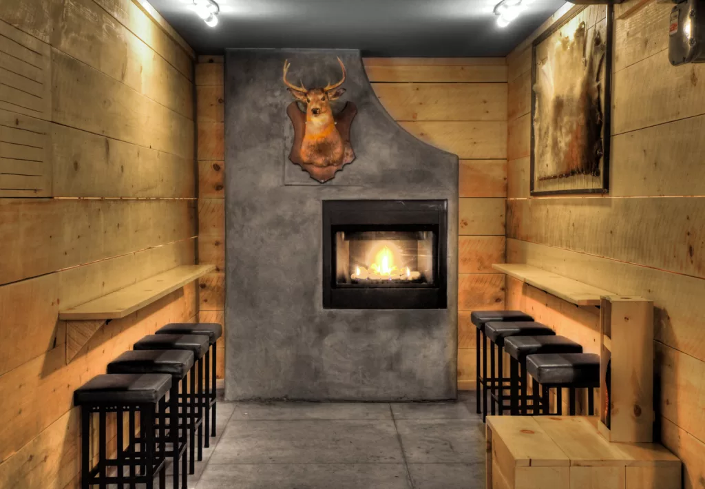 Un faux foyer de béton orné d'un trophé de chasse dans l'un des espaces faits de bois de couleur naturelle du bar Miss Villeray.