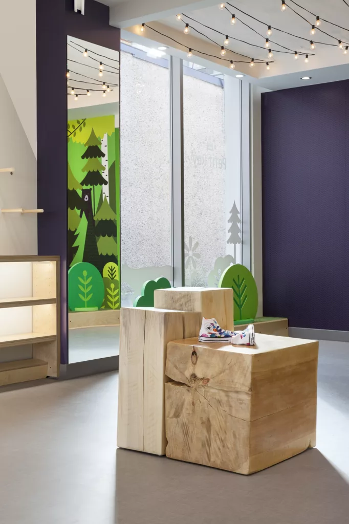 Détail de la boutique. On y voit la murale en reflet dans le miroir. De gros blocs de bois servent de présentoirs.