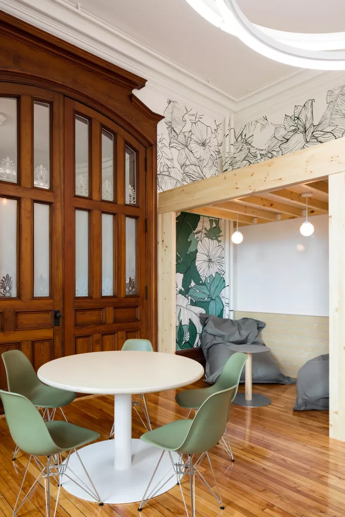 La section à l'entrée du salon créatif du pensionnat Saint-Nom-De-Marie comprend une table ronde et un espace lecture avec des fauteuils-poires.