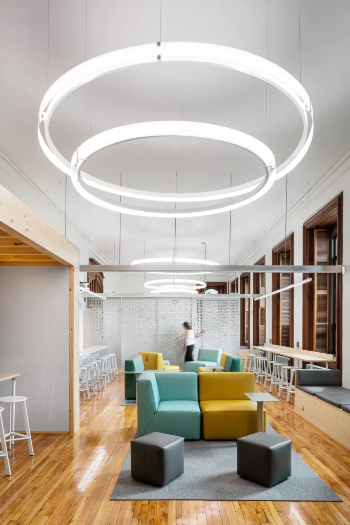Le salon créatif du pensionnat Saint-Nom-De-Marie est éclairé par de grandes lampes circulaires suspendues.