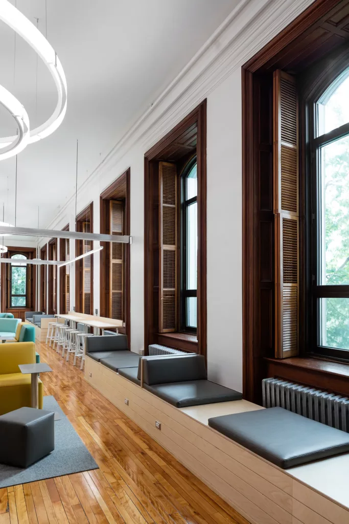 Le mur fenestré du salon créatif du pensionnat Saint-Nom-De-Marie comprend plusieures banquettes de lecture et des tabourets devan un comptoir pour que le plus de gens puissent profiter de ses fenêtres.