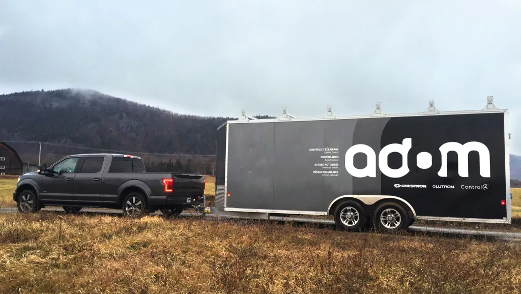 Une roulotte tirée par un camion arborant le logo des la compagnie Adom.