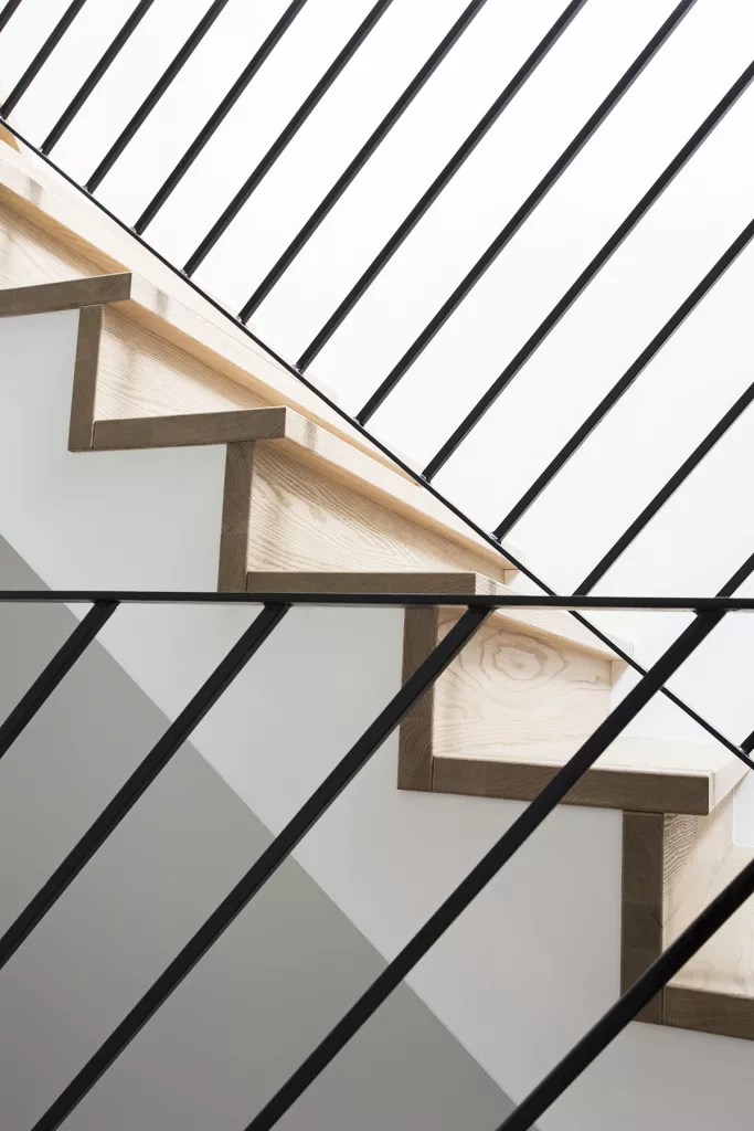 Les angles des rampes d'escaliers créent un effet de perpendicularitéé par rappot à l'escalier de bois clair.
