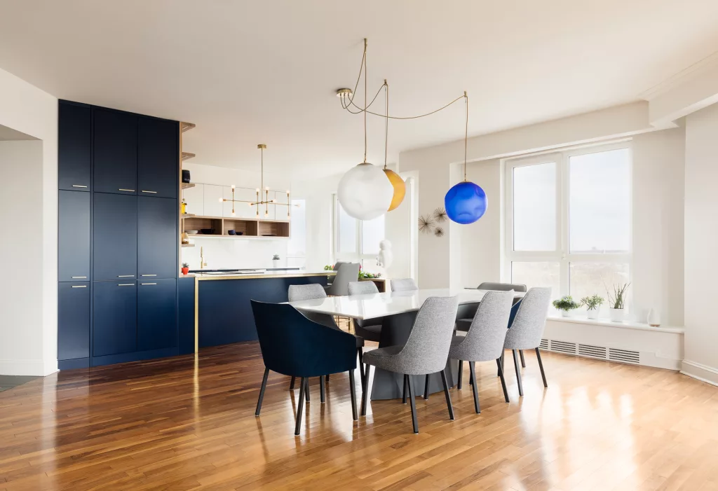 Des lampes suspendues au dessus de la table de cuisine en marbre et acier rappellent les teintes de marine, laiton et marbre de la cuisine.