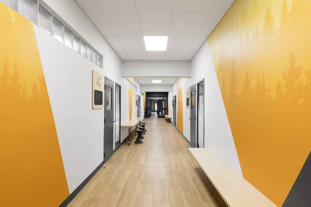 Des murales colorées imprimées de silhouettes de foret dynamisent un corridor du Séminaire Sacré-Coeur.