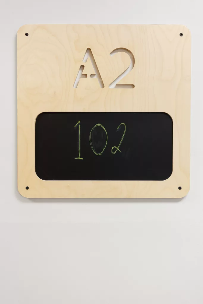 La signalétique de bois clair comprend un espace personnalisable comme un minuscule tableau noir.