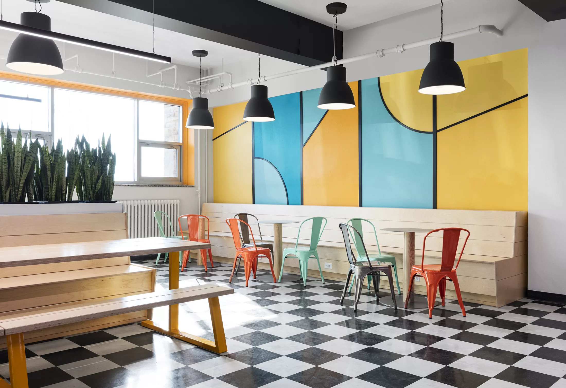 Le salon étudiant du Séminaire Sacré-Coeur est dynamisé âr l'ajout de mobilier à l'essence de bois et de couleurs vives.