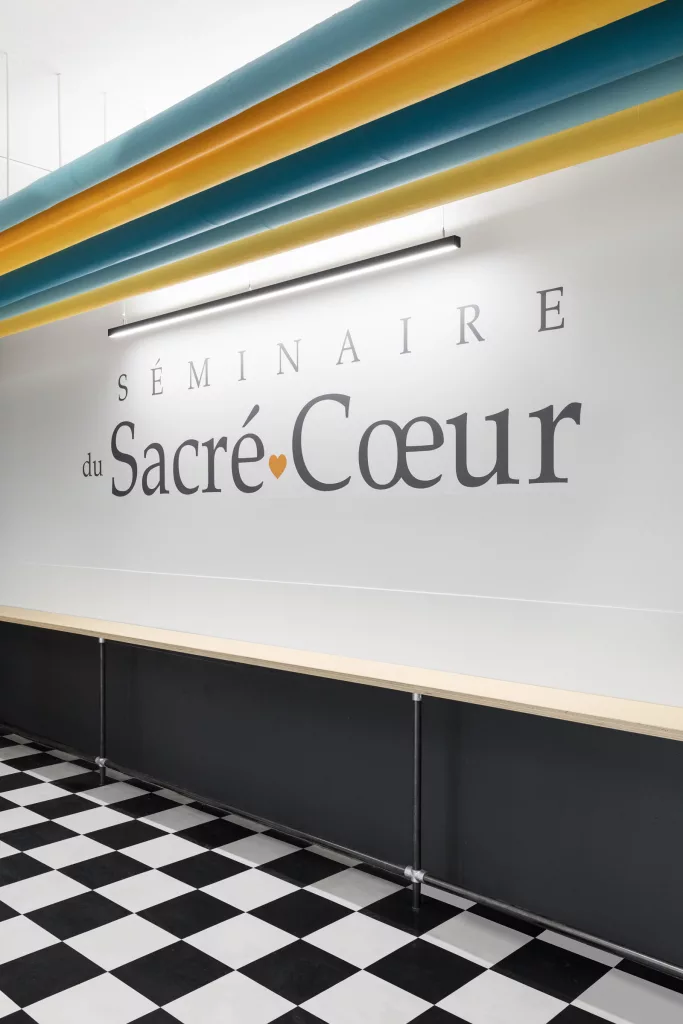 Les tuyaux du système de caloréfaction ont été peints de coulerus attrayantes au -dessus d'un logo mural dans le salon étudiant.