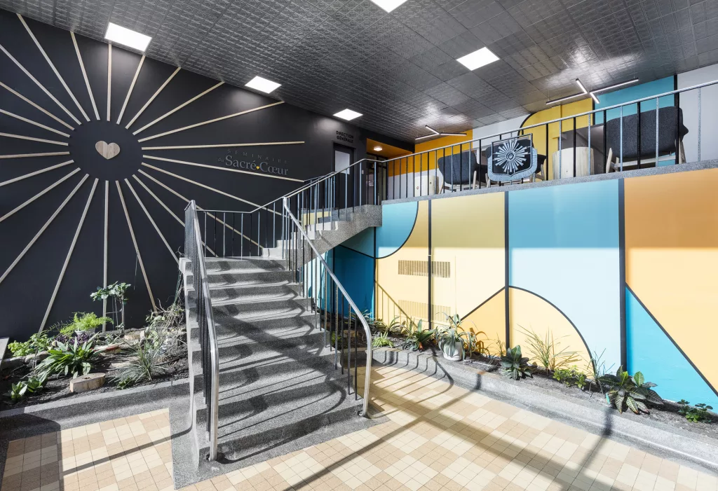 Une vue diagonale de l'escalier motre les couleurs de la murale qui se retrouvent également sur le mur du second étage.