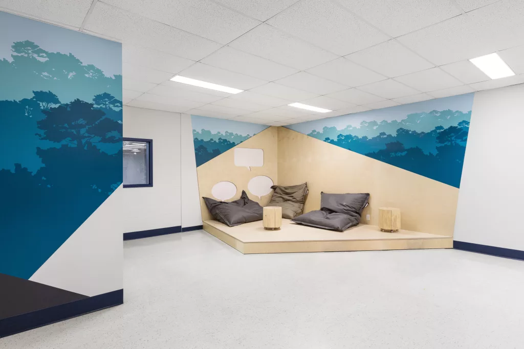 Le coin lecture contien du mobileir confortable et est fait d'un plancher sumonté et des formes murales en bois clair.