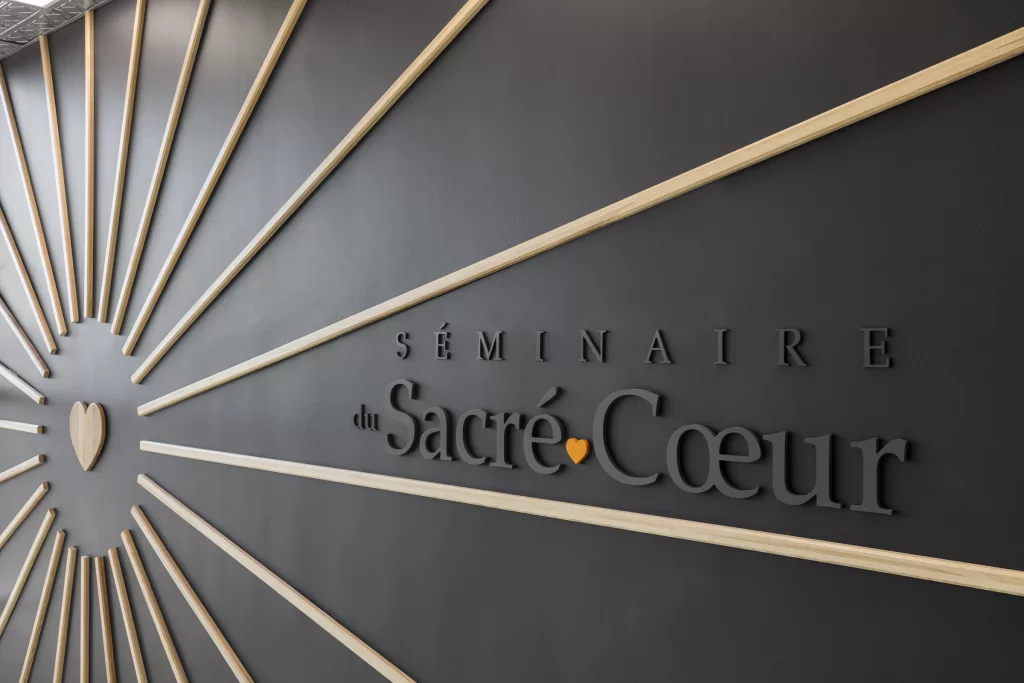 Un logo du Séminaire Sacré-Coeur appliqué sur le mur dans les faisceaux d'un coeur rayonnant.