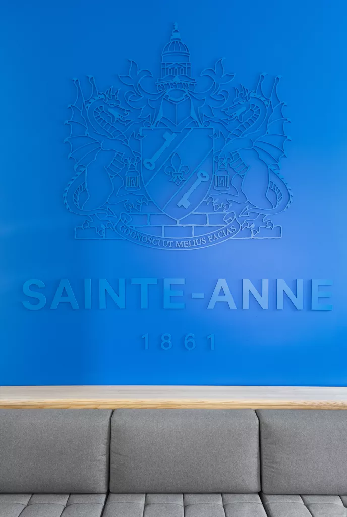 Dans la salle d'attente, les armoiries tridimentionnelles du collège Sainte-Anne  sont apposées au mur.