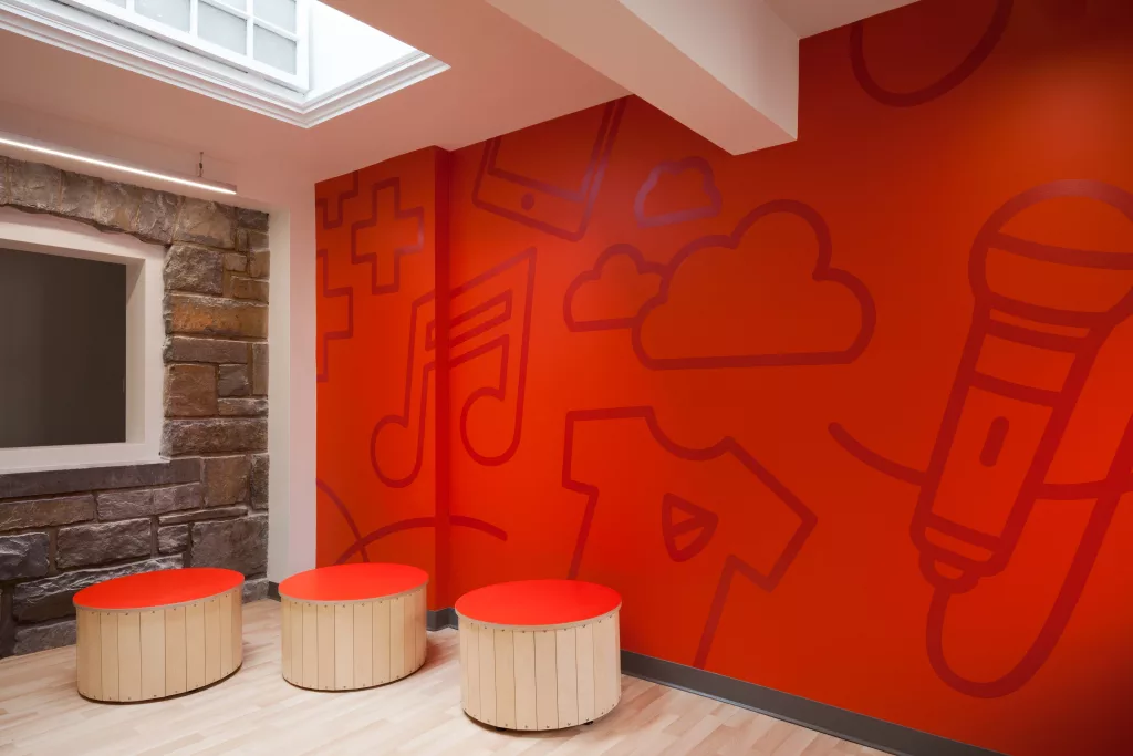 Des bancs mobiles devant une murale dans la salle de musique de l'Académie Sainte-Anne.